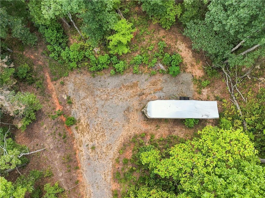Wooded property with a gravel clearing and a long white trailer.