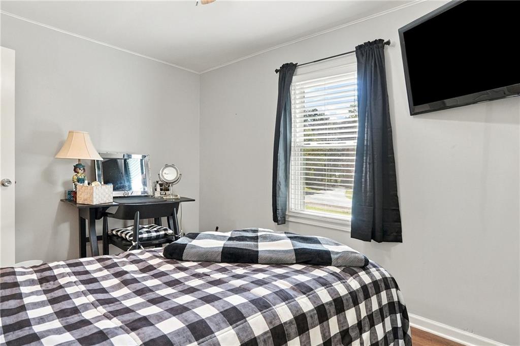 Bedroom with a black-and-white checkered bedspread, desk, and window with dark curtains.