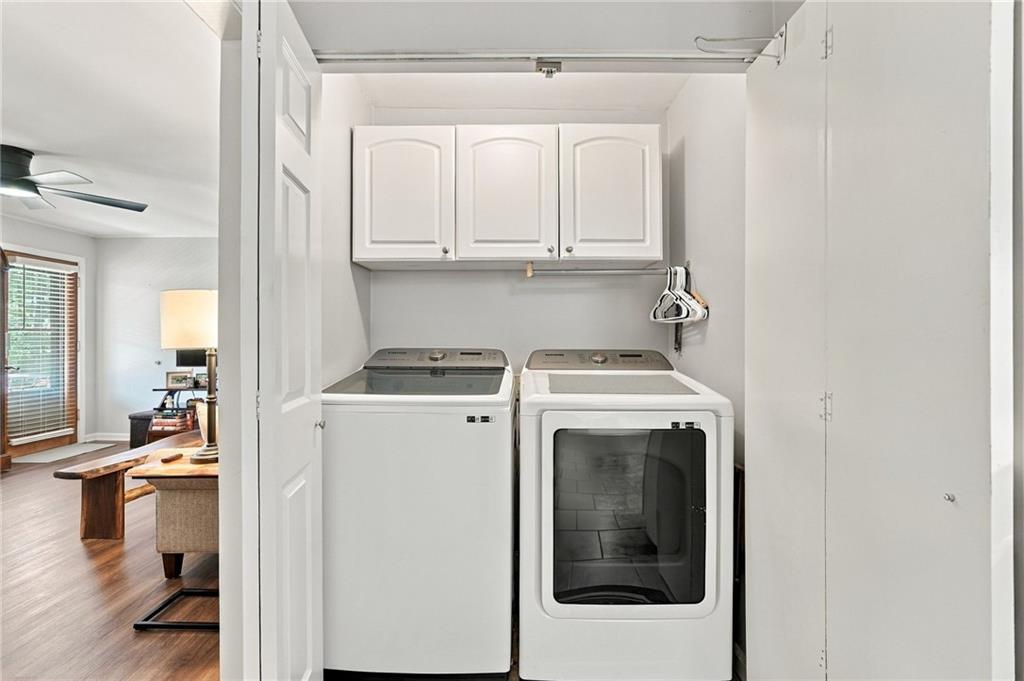 Laundry area with a top-load washer, front-load dryer, and overhead cabinets.