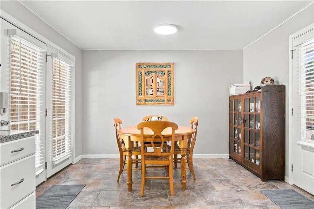Dining room with a wooden table and chairs, tiled floor, and glass-front cabinet.