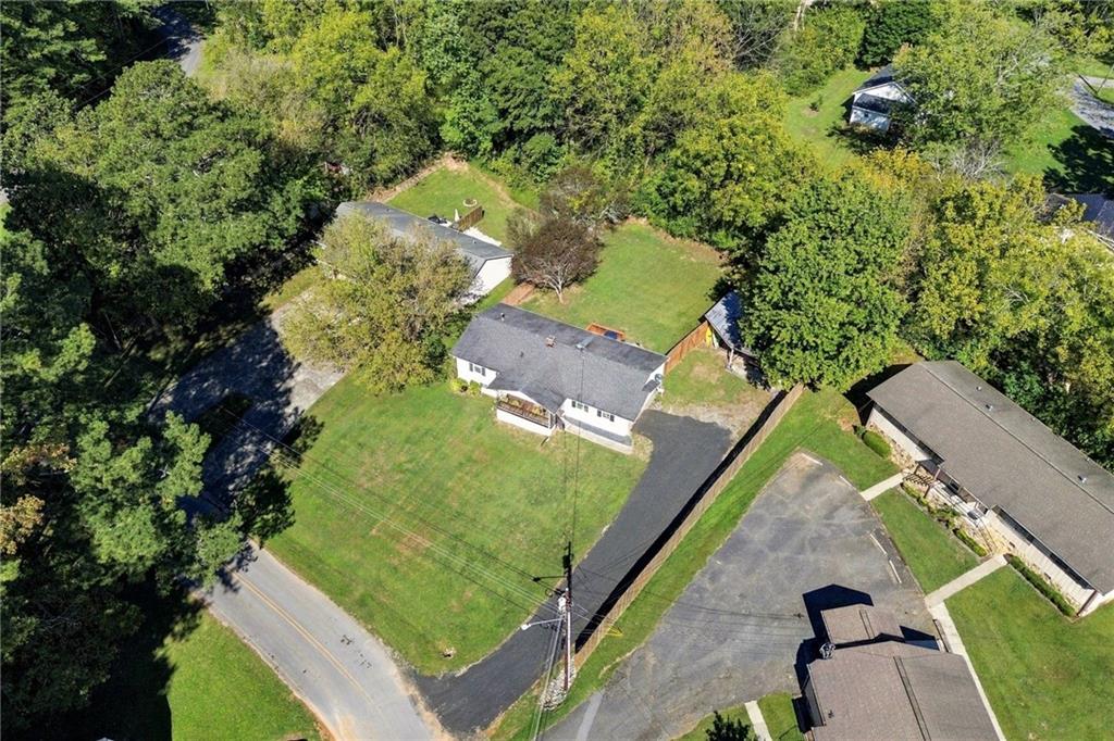 Aerial view of a white house, broad lawn, driveway, and surrounding trees.