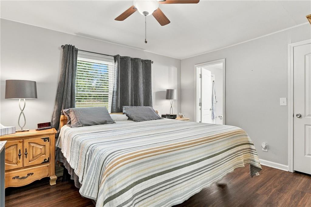 Bedroom with a striped bedspread, dark curtains, and wood flooring.