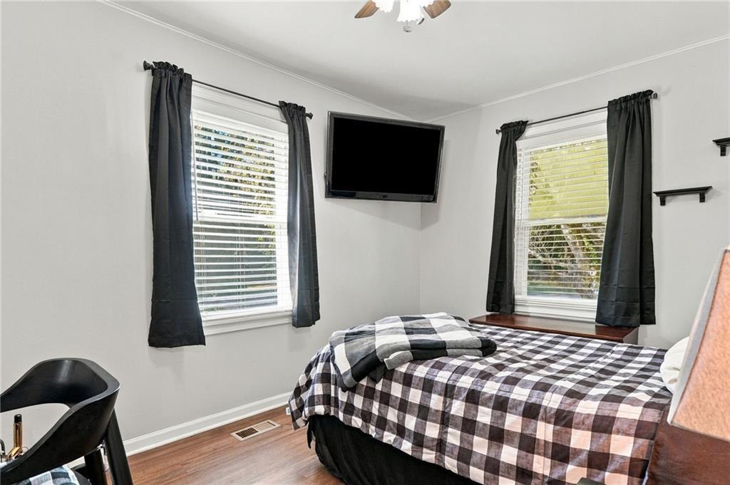 Bedroom with a black-and-white checkered bedspread, two curtained windows, and a wall-mounted television.