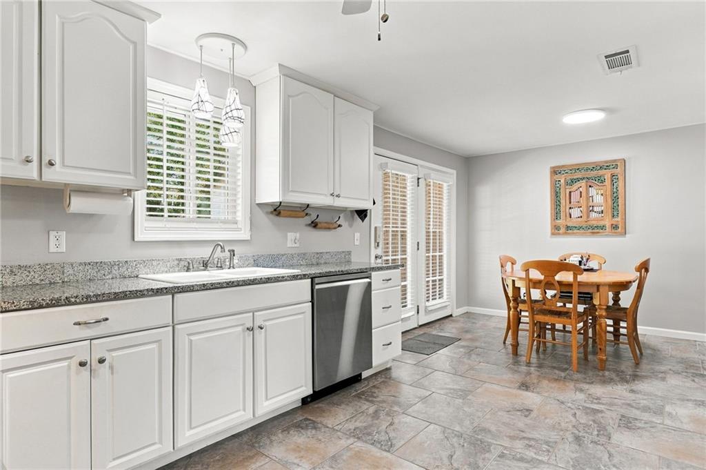 Kitchen and dining area with white cabinets, granite counters, and a wooden table by the French doors.