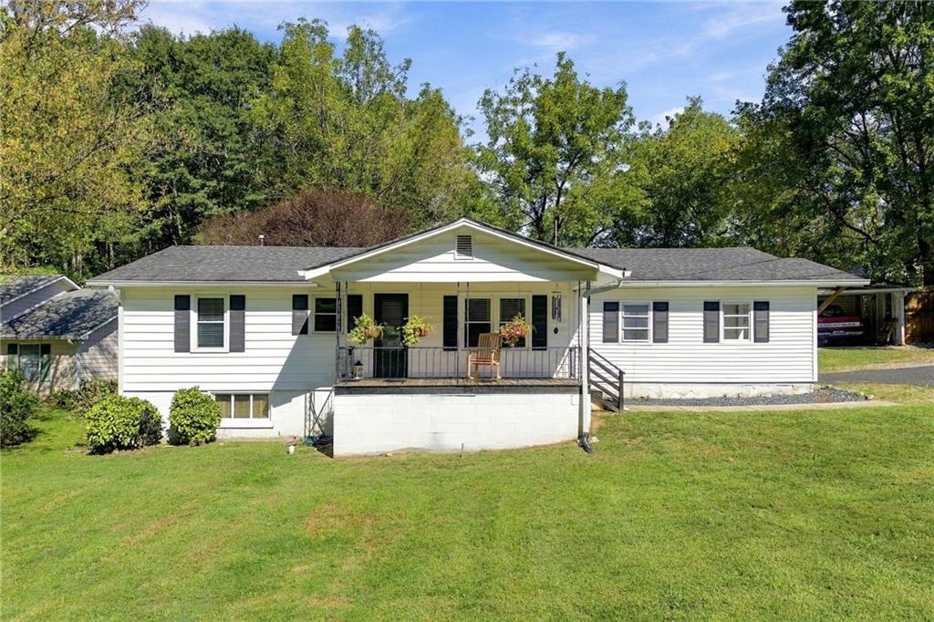 Single-story white ranch home with a covered front porch, broad lawn, and mature trees.