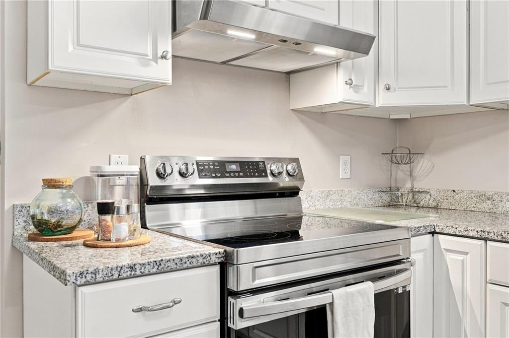 Kitchen with a stainless steel range, white cabinets, and granite countertops.