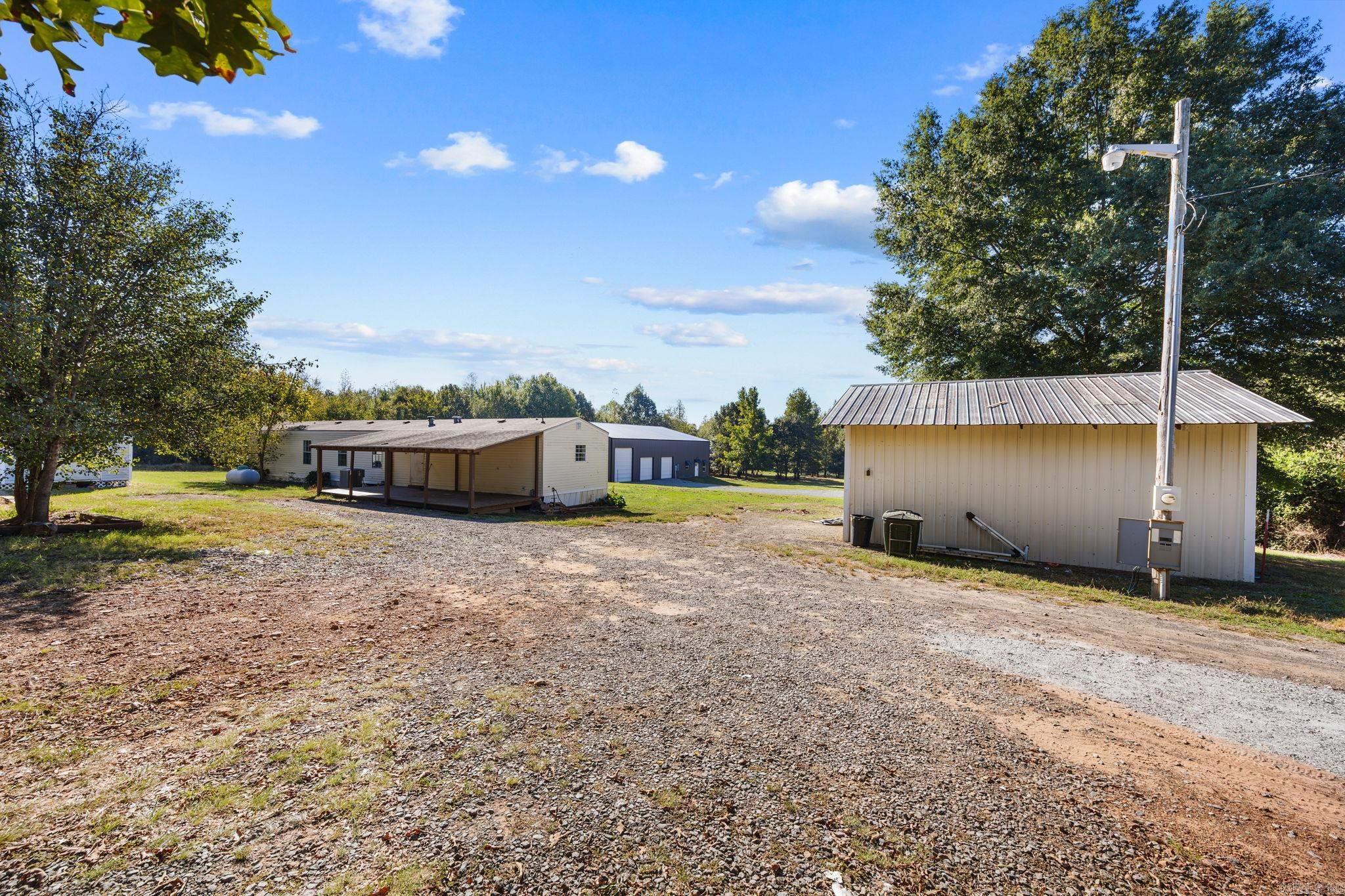 Property exterior with a gravel drive, covered porch, and detached metal outbuilding.