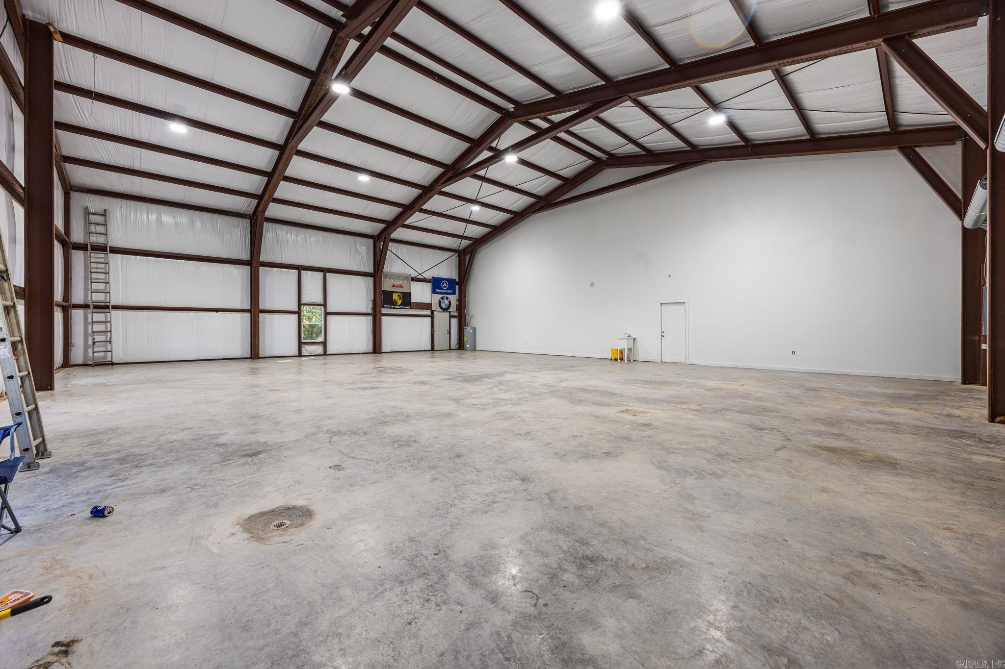 Large empty metal-frame workshop with a high exposed-beam ceiling and concrete floor.
