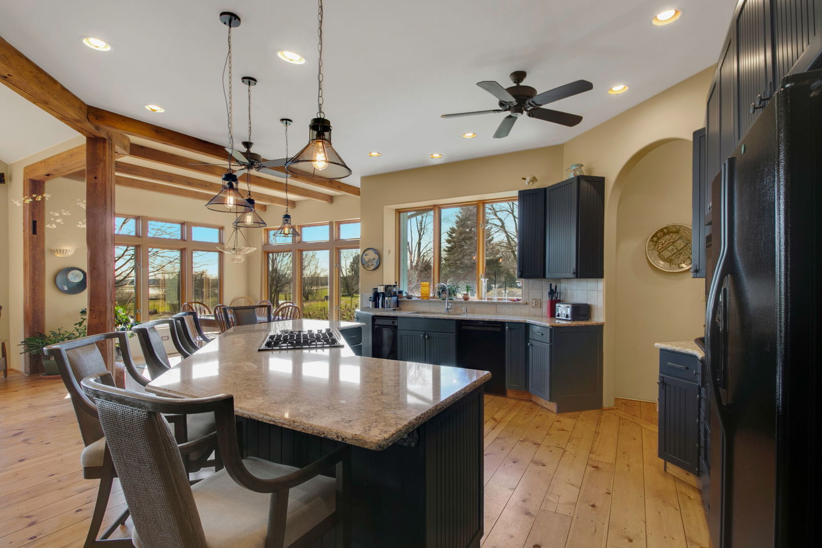 Kitchen and dining area with a large island, exposed timber beams, and tall windows.