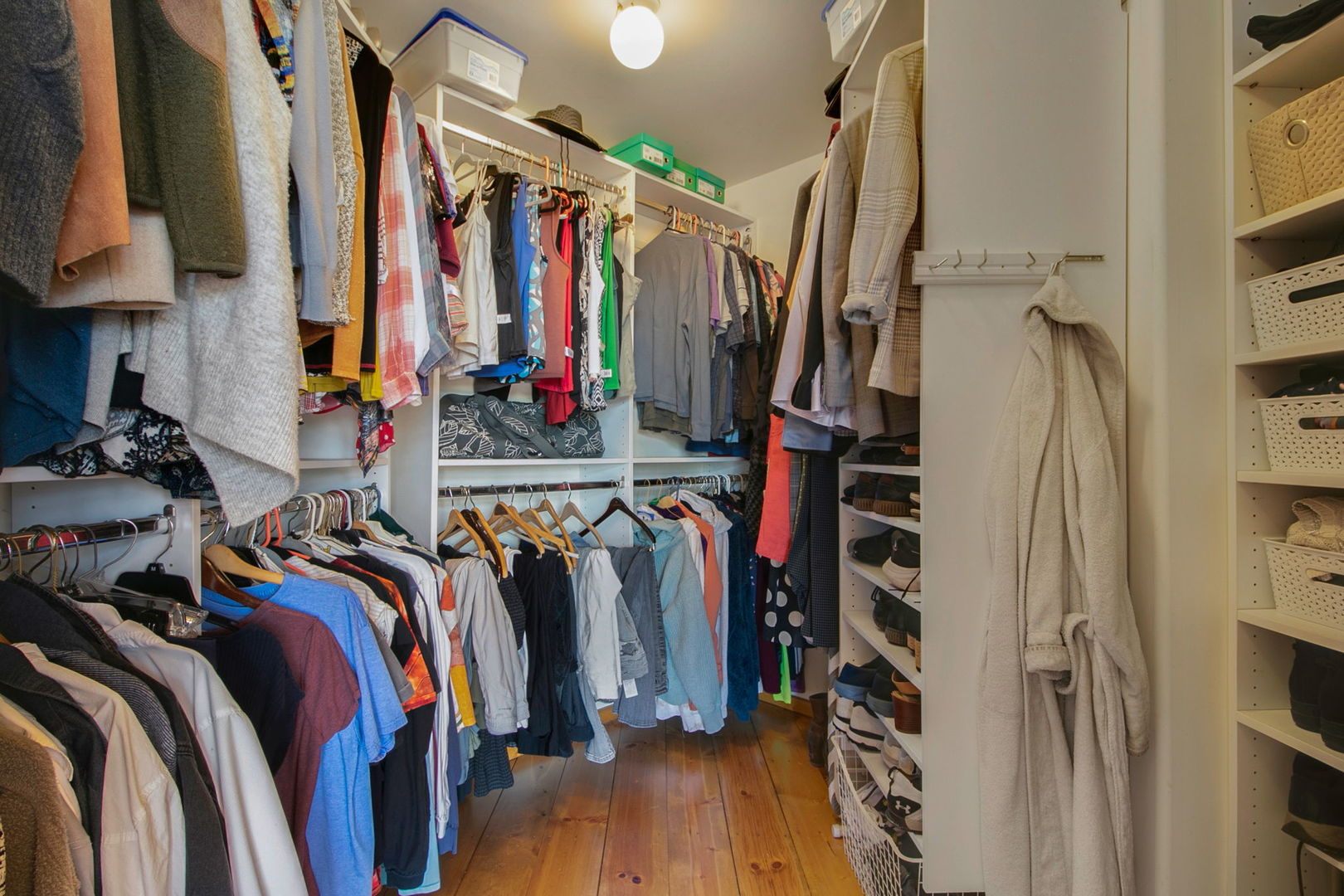 Walk-in closet with extensive clothing storage, built-in shelves, and wood flooring.