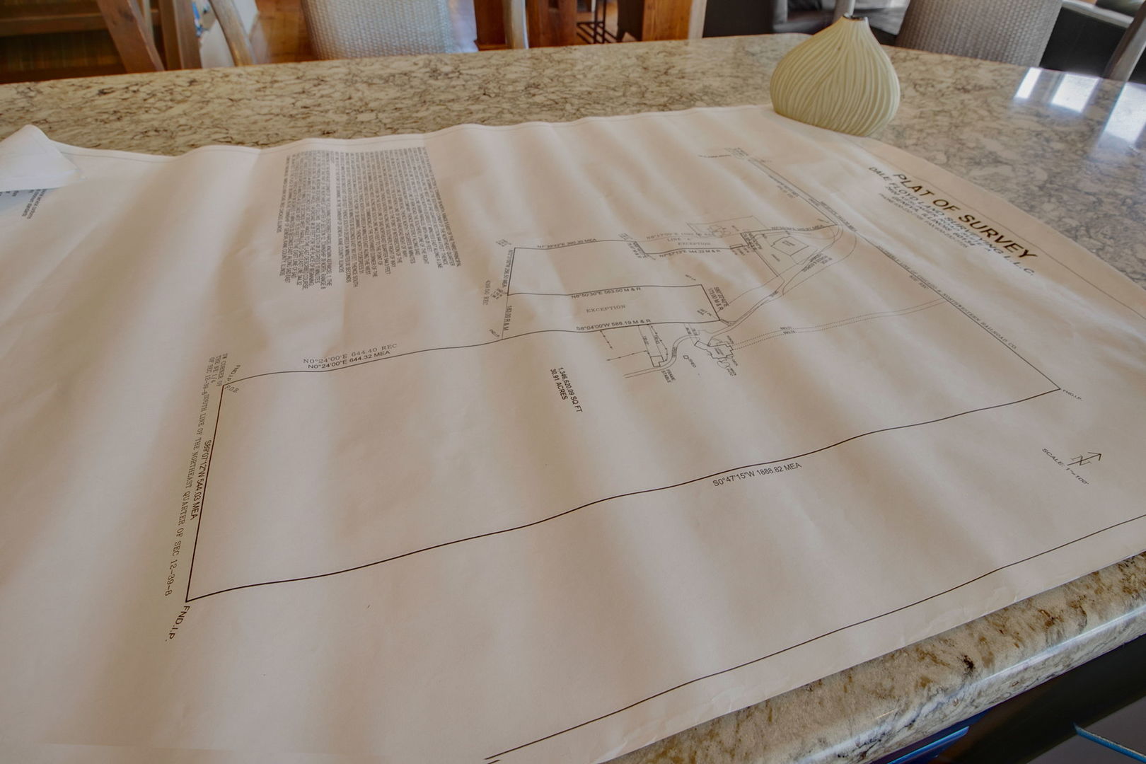 A property survey plat spread across a granite countertop.