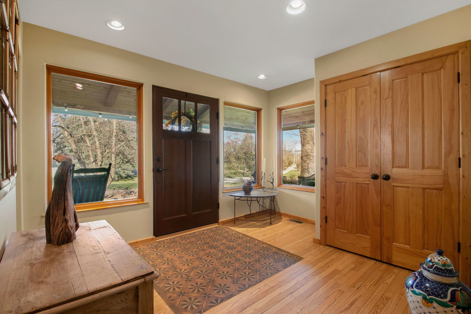Home entryway with a dark wood front door, large windows, hardwood floors, and a patterned tile inset.