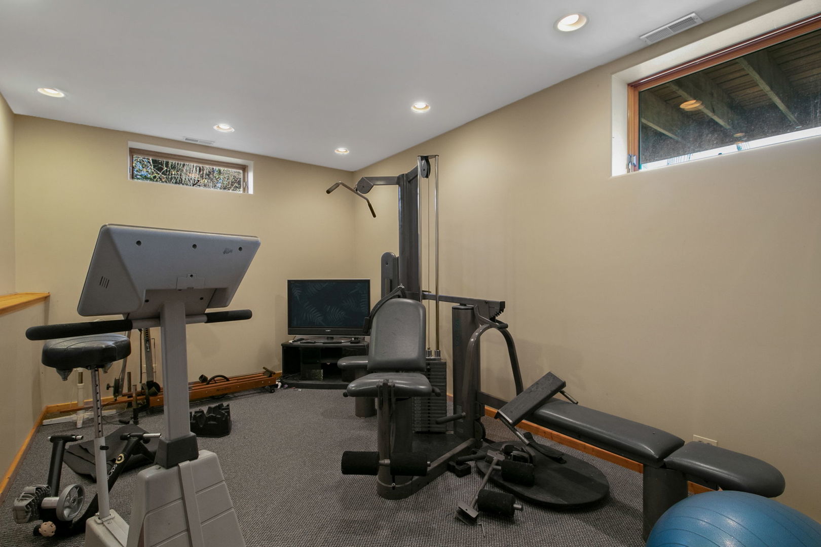 Home gym with multiple strength-training machines, a weight bench, and a blue exercise ball.