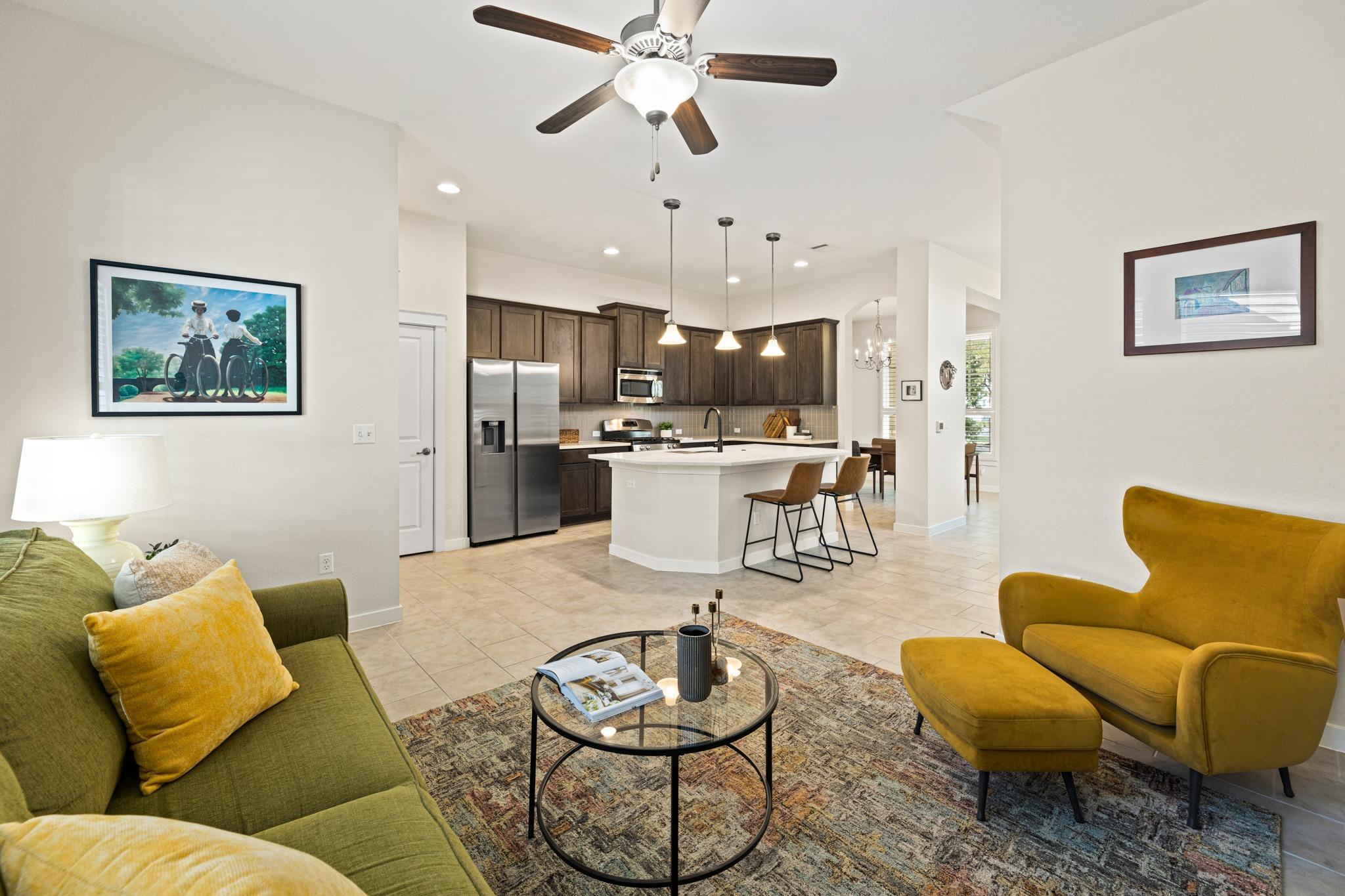 Open living room and kitchen with a white island and colorful seating.