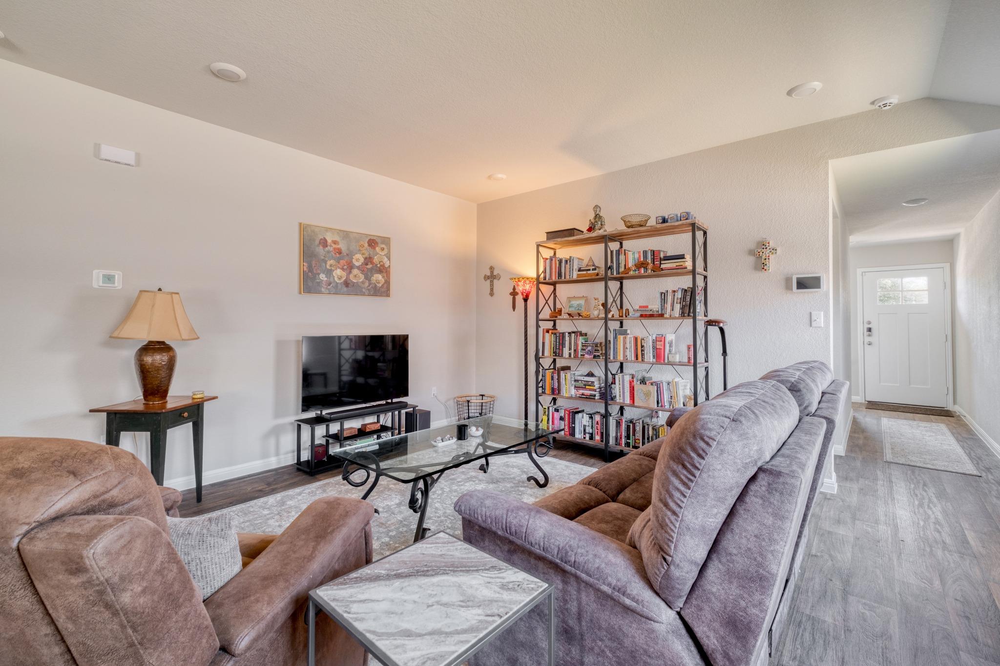 Living room with plush sofas, a full bookshelf, and a glass coffee table.