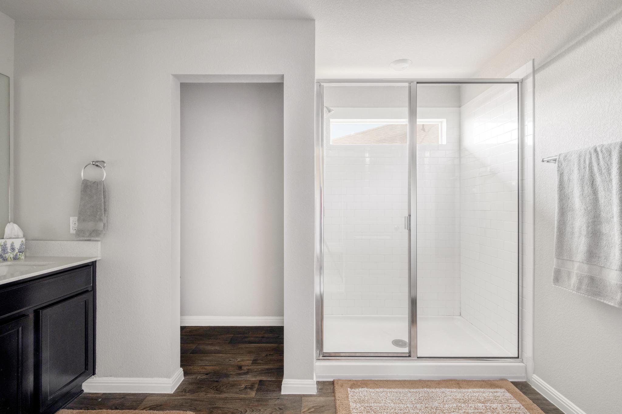 Bathroom with a glass-enclosed white-tile shower and dark vanity.