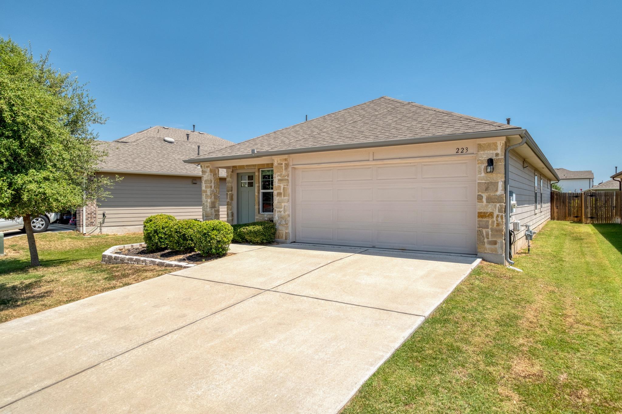 Single-story home with stone accents, a two-car garage, and a wide concrete driveway.