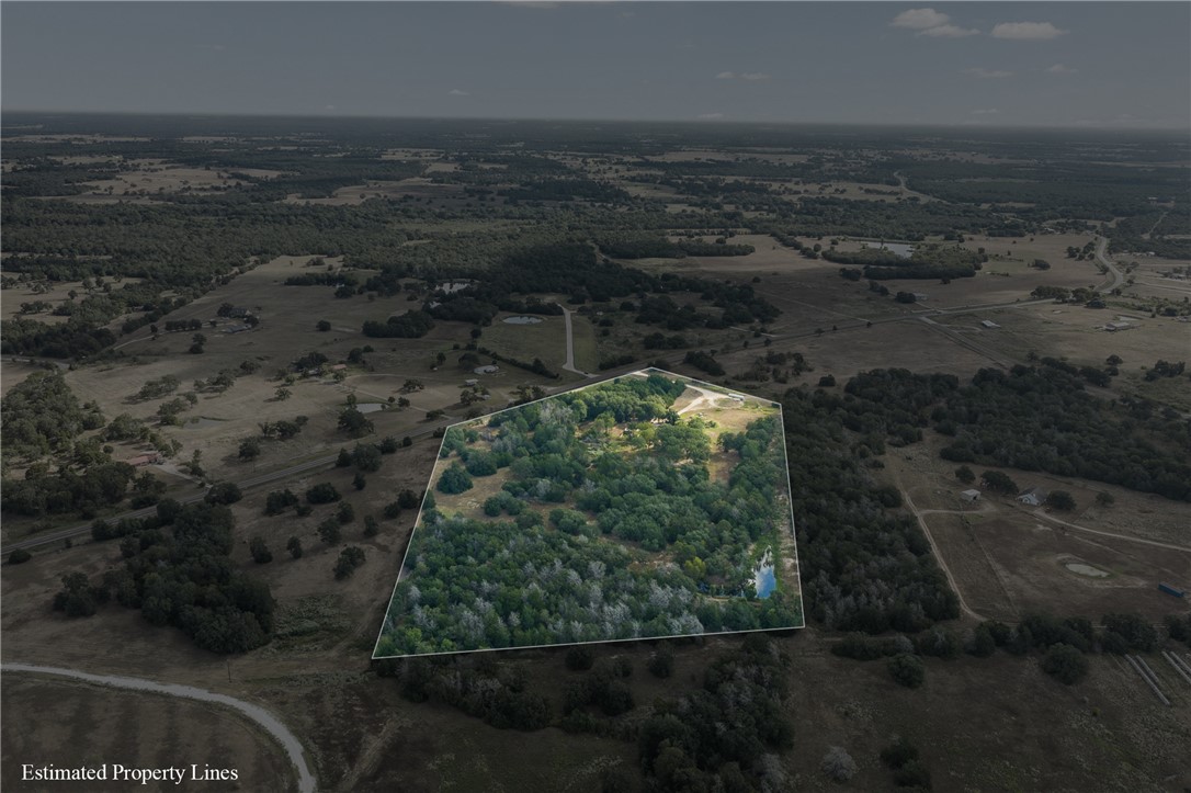 Aerial view of wooded acreage outlined by estimated property lines, with clearings and a small pond.
