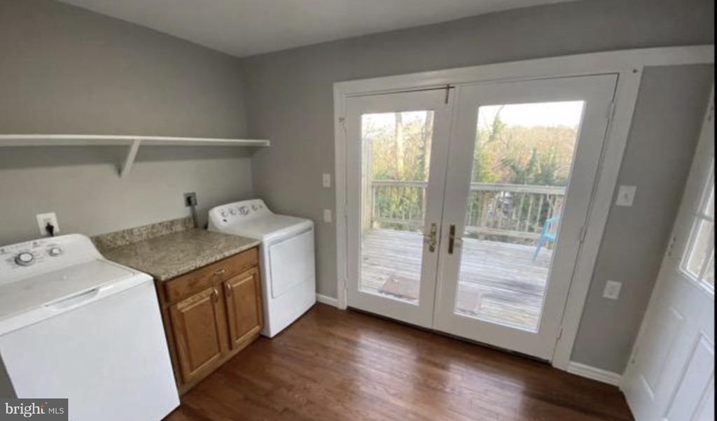Laundry room with washer and dryer, wooden cabinets, and French doors to a deck.