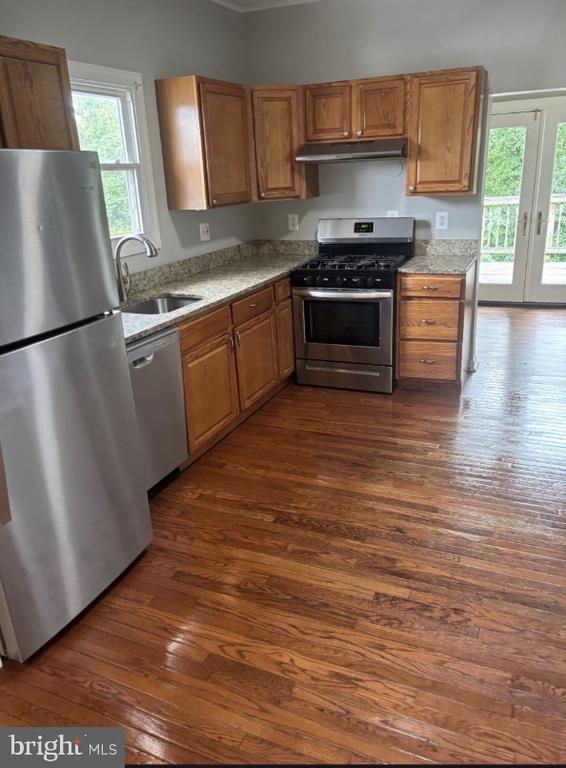 Kitchen with wood cabinets, granite counters, stainless steel appliances, and hardwood floors.