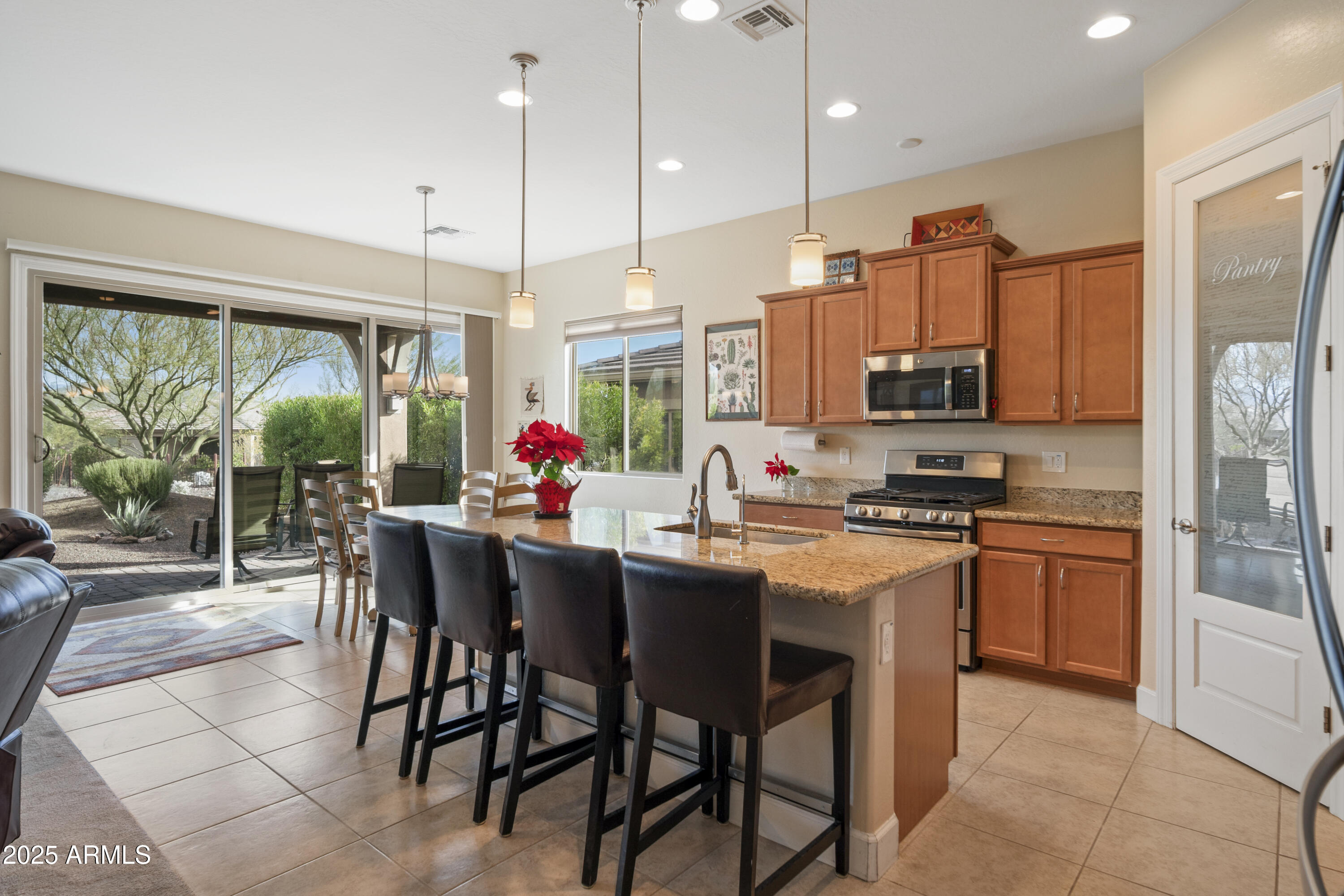 Kitchen with granite island and bar stools beside sliding glass doors to a landscaped patio.