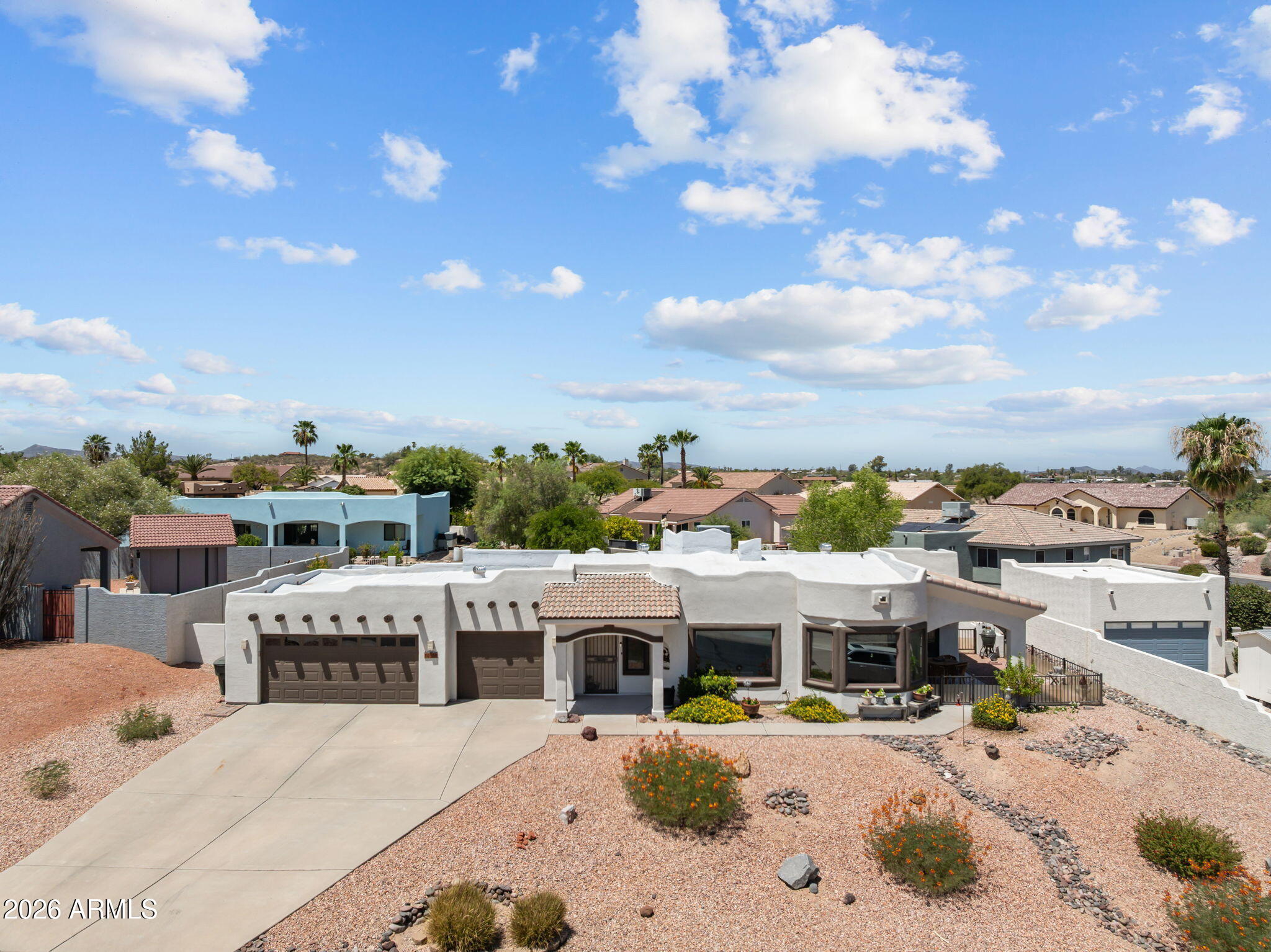 Stucco home with a tiled entry, double garage, broad driveway, and desert gravel landscaping.