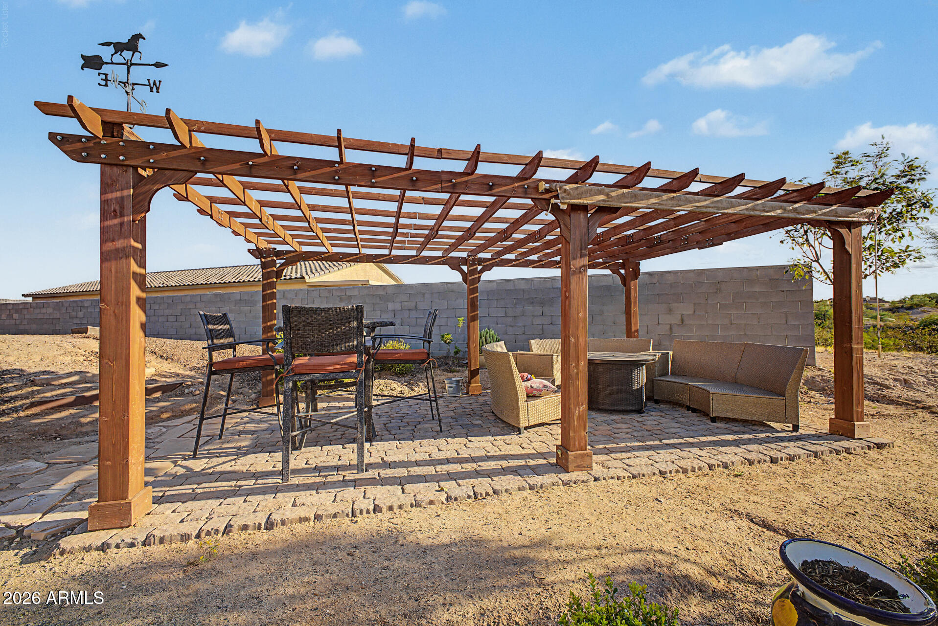 Backyard patio with a wooden pergola, paver flooring, and outdoor dining and lounge seating.