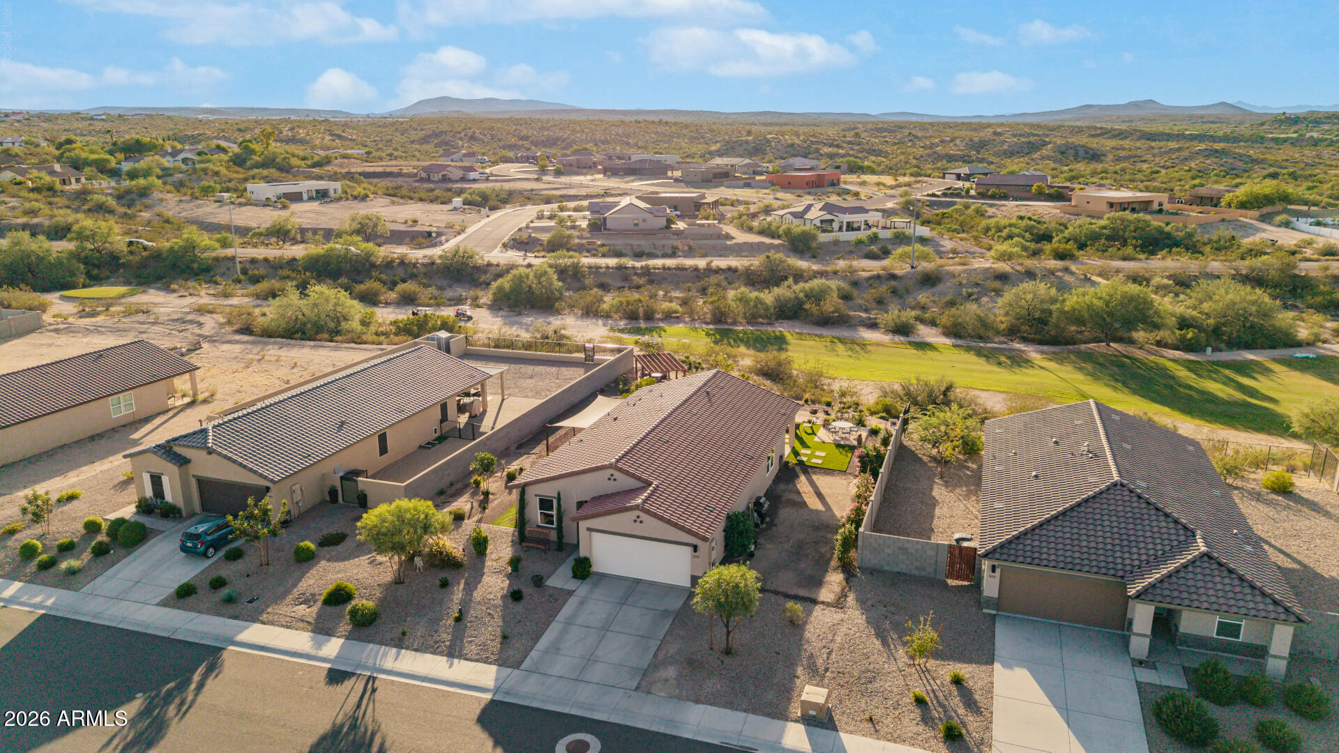 Aerial view of desert neighborhood homes with distant mountain ridges.