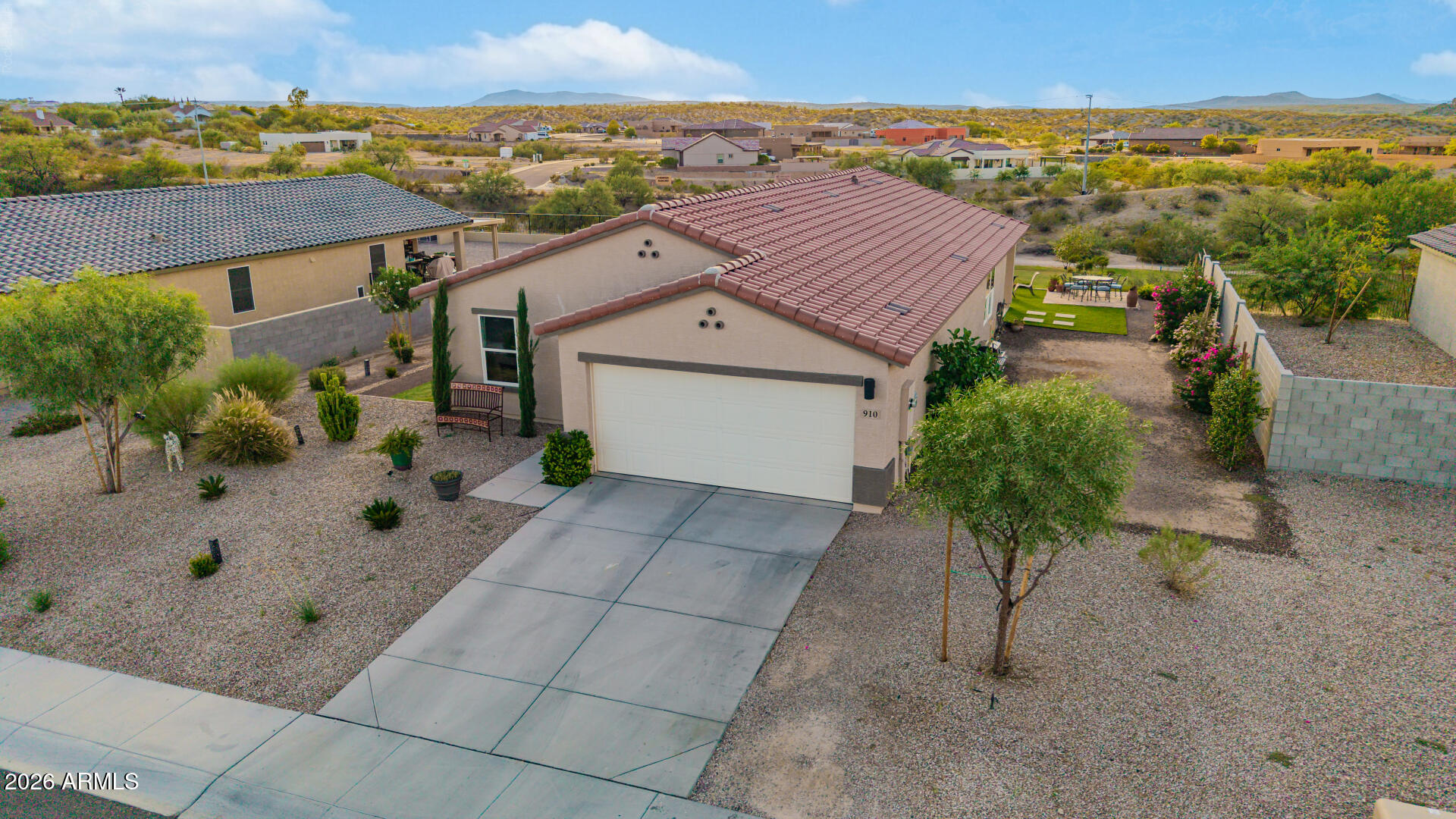 Single-story stucco home with a red tile roof, desert landscaping, and a fenced patio.