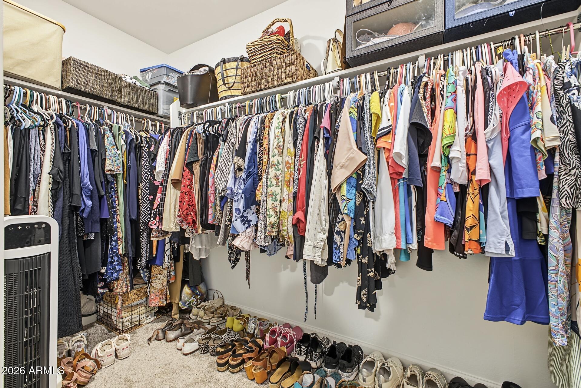 Walk-in closet with extensive clothing racks, storage baskets, and rows of shoes.