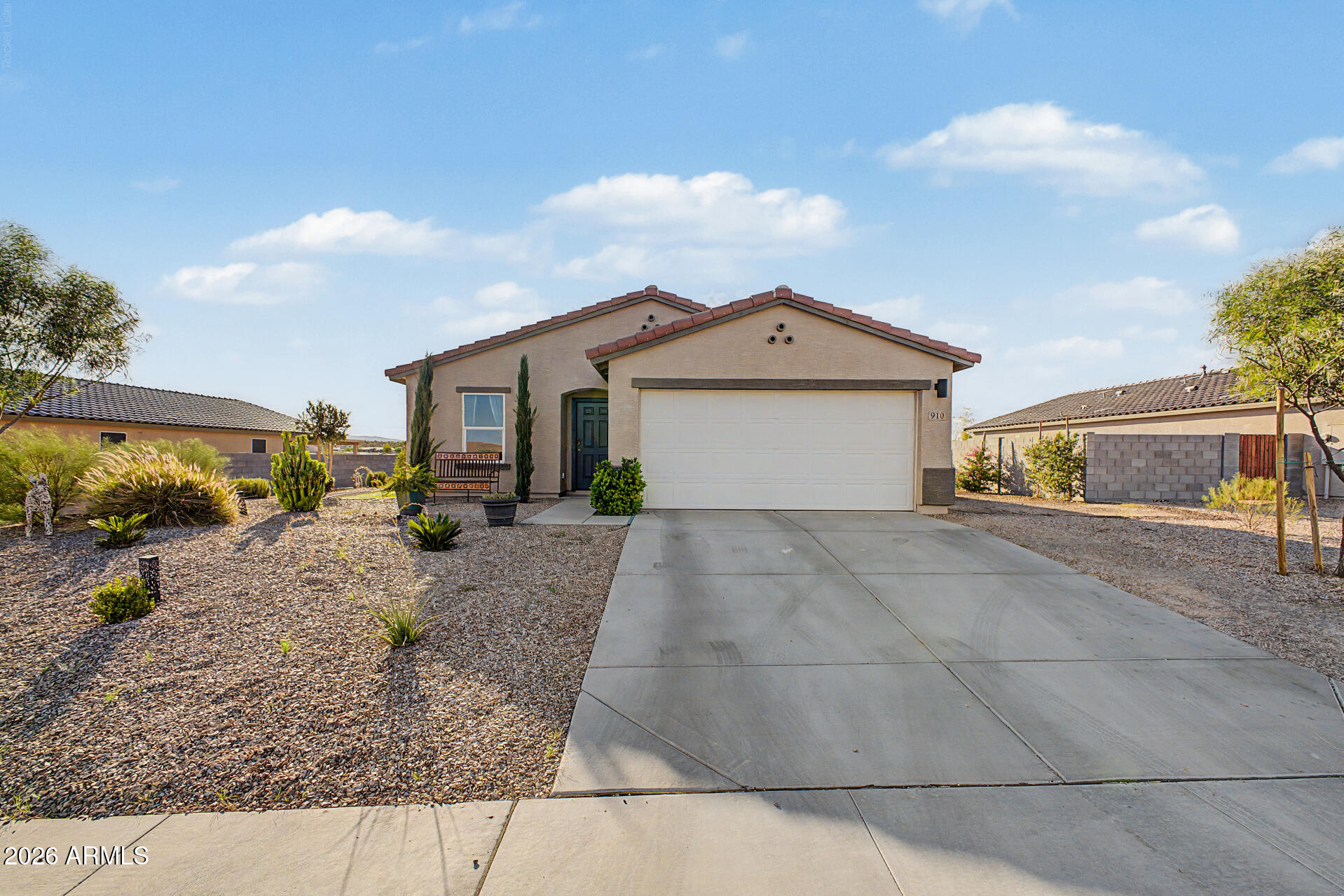 Single-story stucco home with a two-car garage, wide driveway, and desert gravel landscaping.