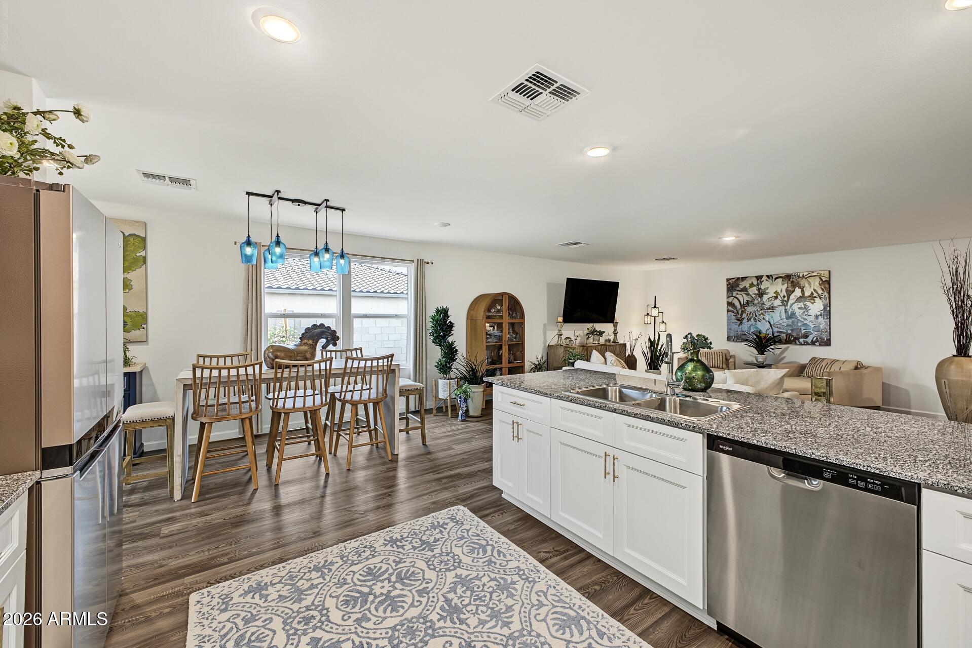 Open-plan kitchen and living area with a large granite island and blue pendant lights.