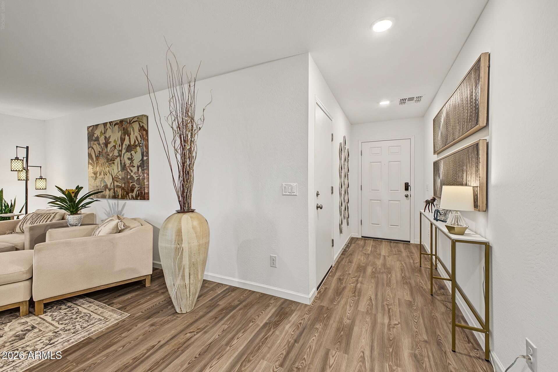 Furnished entryway with wood-look floors, console table, and adjoining beige-sofa living room.
