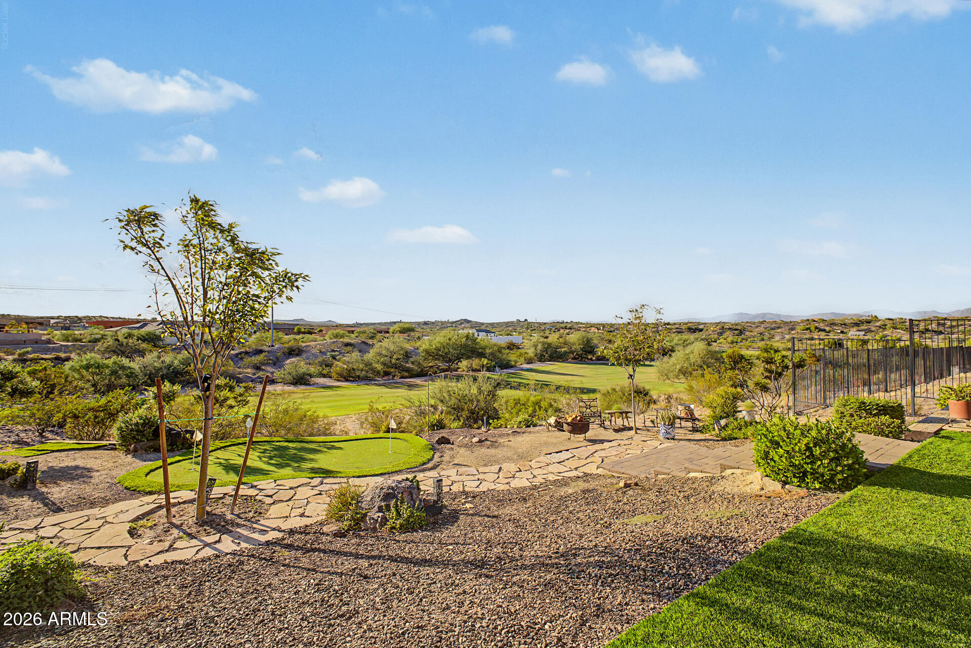 Backyard putting green and stone paths overlook a golf course and desert landscape.