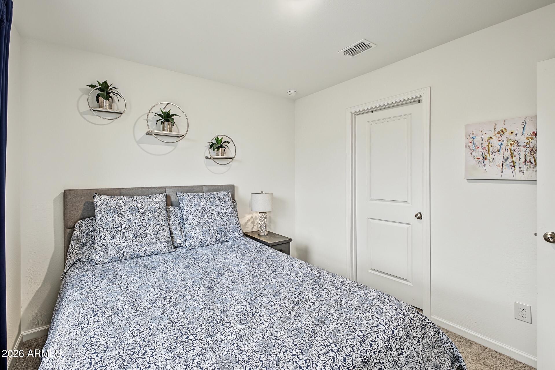 Bedroom with blue-and-white floral bedding, a gray headboard, and circular plant shelves above the bed.