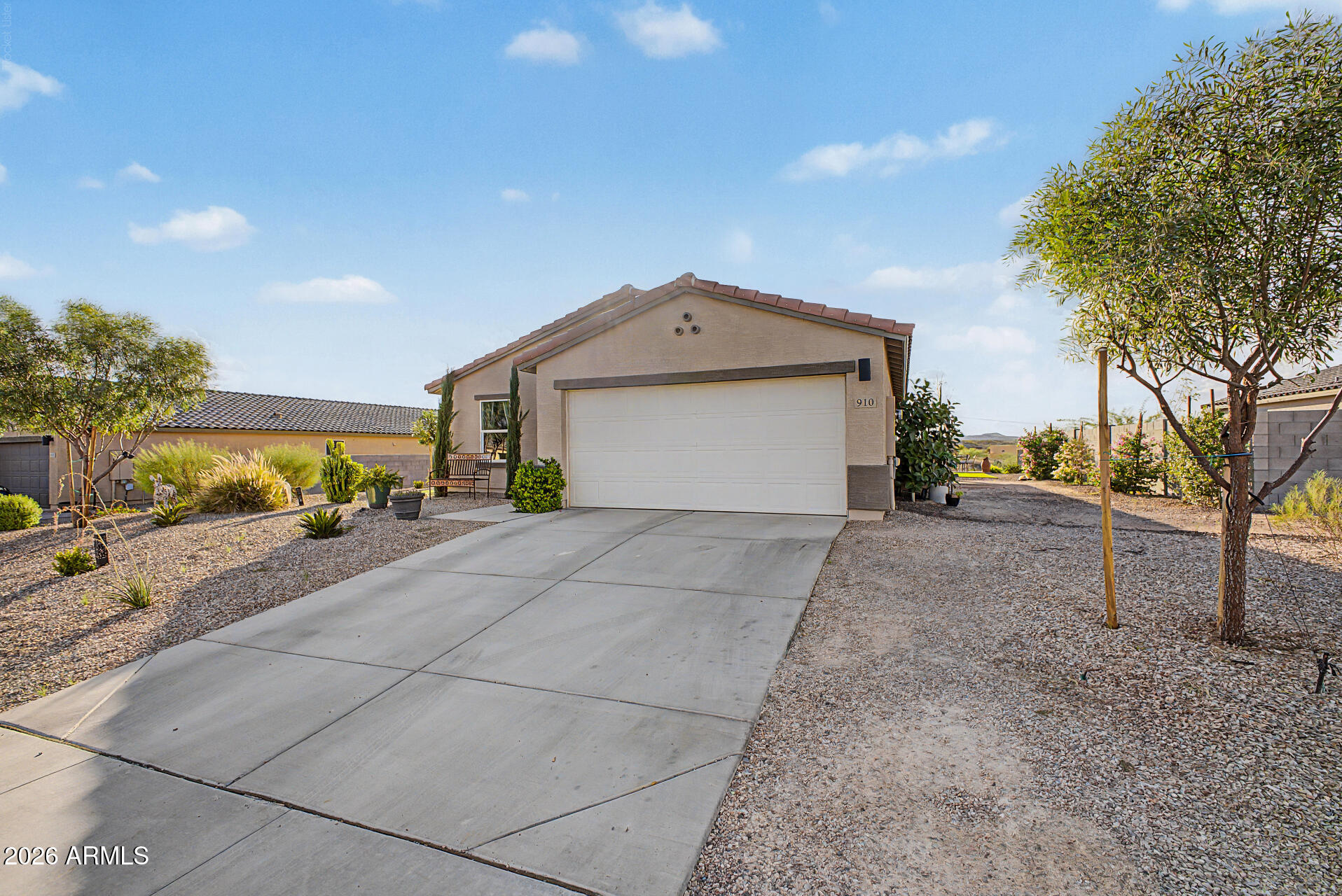 Single-story stucco home with a two-car garage, wide driveway, and desert landscaping.