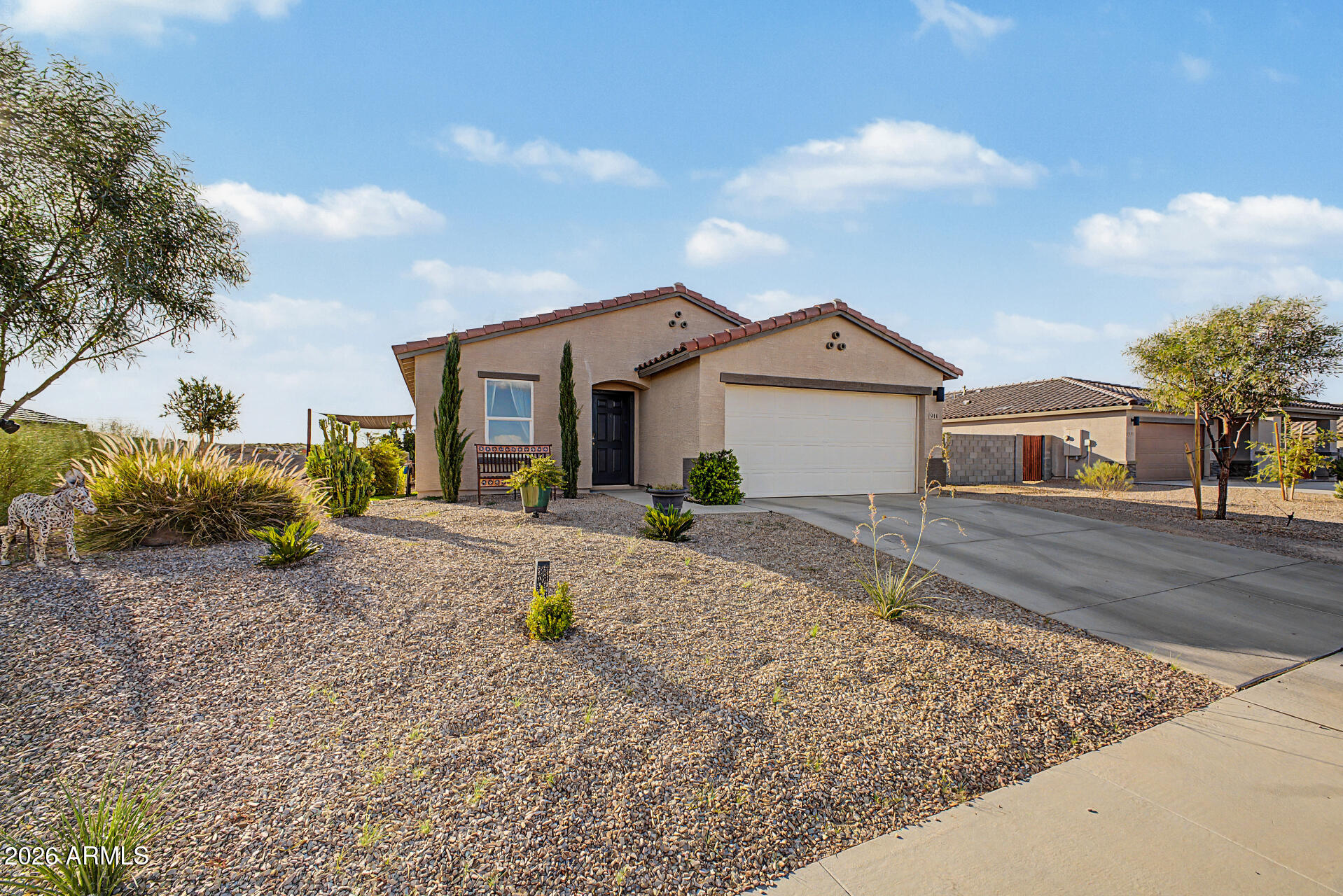 Single-story stucco home with a two-car garage, red tile roof, and gravel desert landscaping.