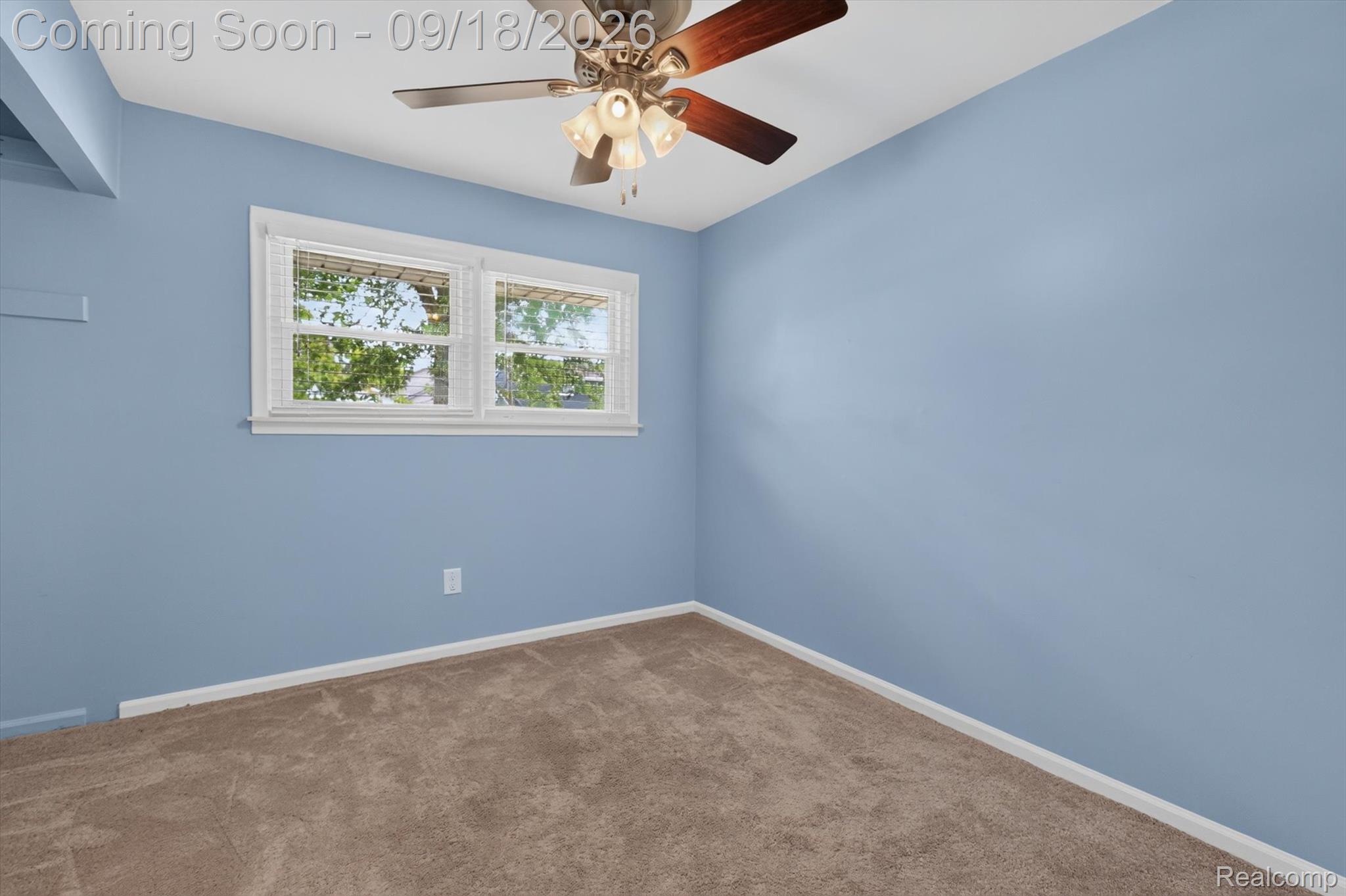 Empty bedroom with blue walls, beige carpet, a double window, and a ceiling fan.