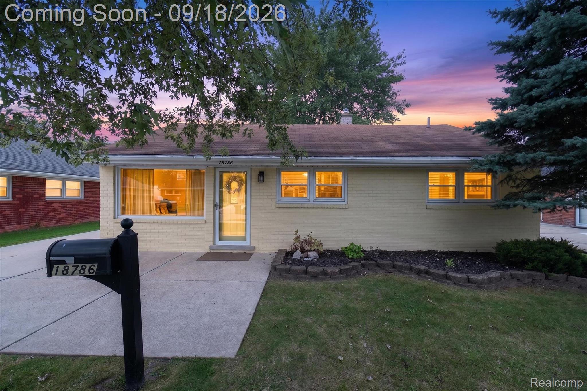 Light-brick ranch home at dusk, with glowing windows and a mailbox marked 18786.