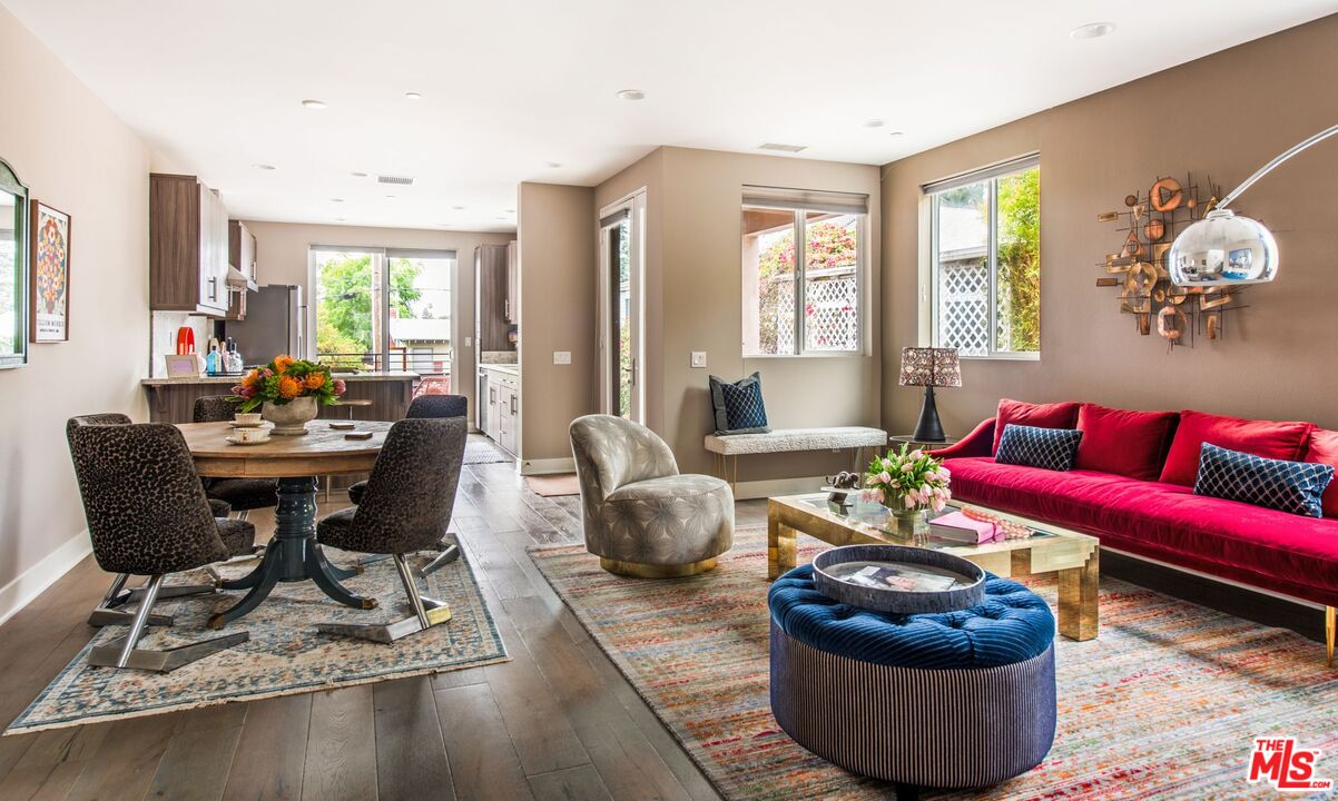 Open-plan living and dining area with a red sofa, round table, and large windows.