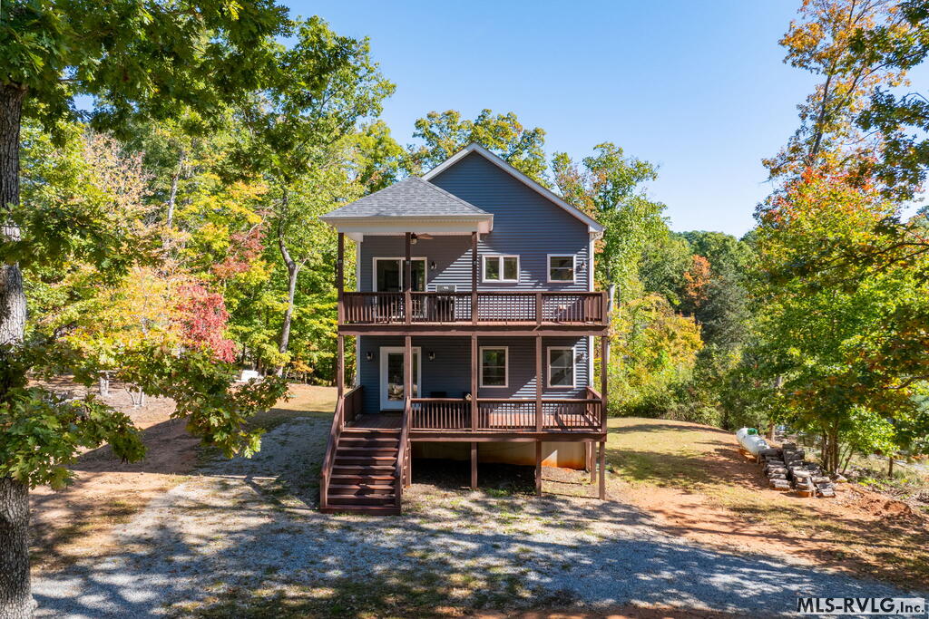 Blue two-story house with stacked covered decks, exterior stairs, and autumn trees.
