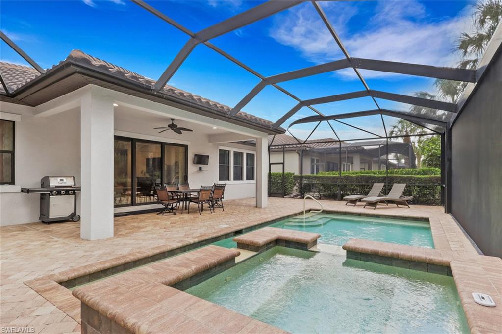 Screened backyard pool and raised spa beside a covered patio with outdoor dining furniture.