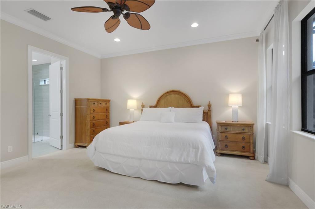 Bedroom with a king bed and wooden furniture, opening to a tiled bathroom.
