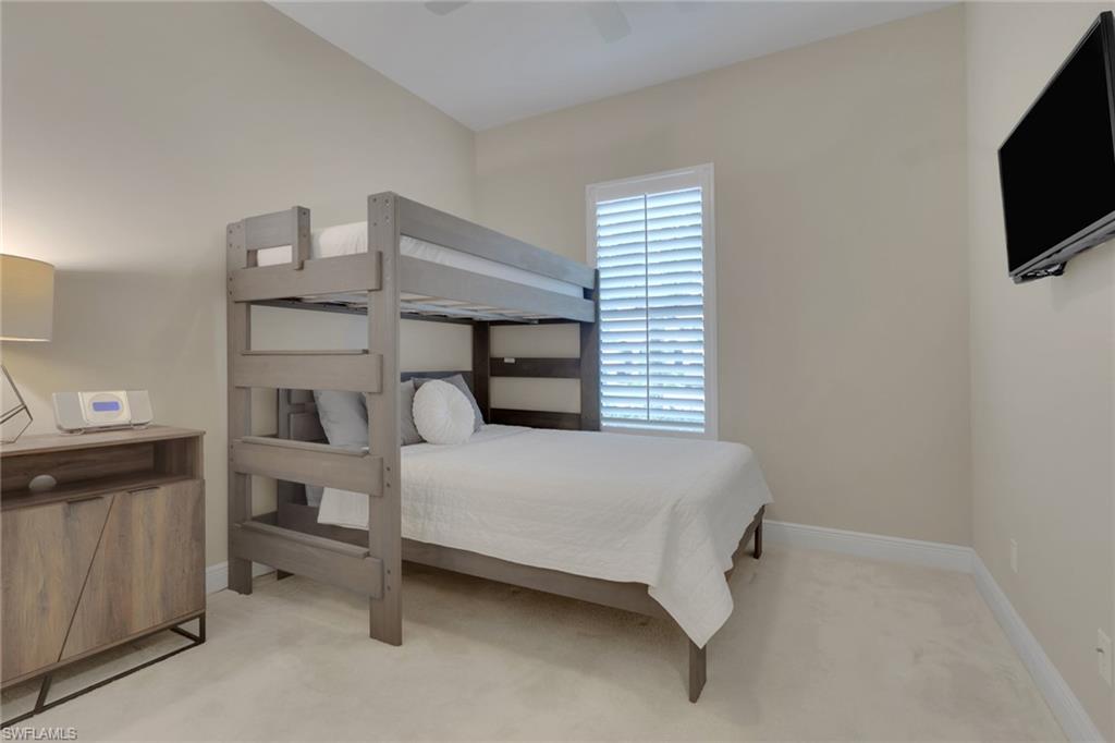 Bedroom with a gray wood bunk bed, white bedding, carpet, and plantation-shuttered window.