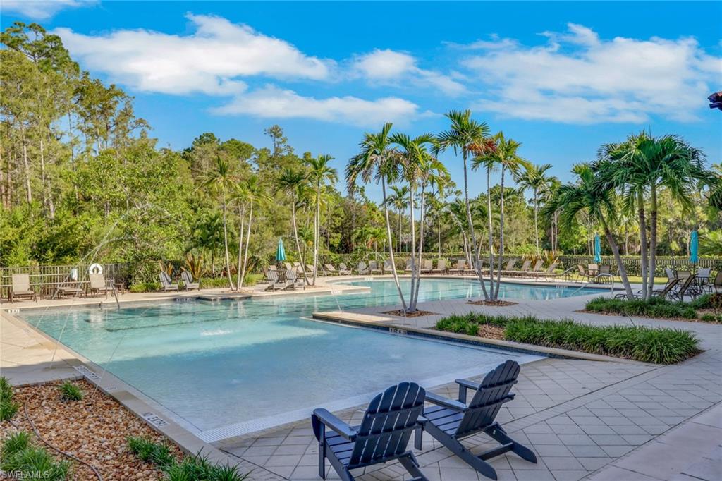 Community swimming pool with palm trees, lounge chairs, and a paved deck.