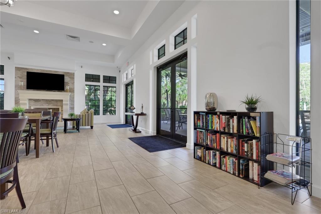 Open living and dining area with a stone fireplace, tall windows, and black-framed glass doors.