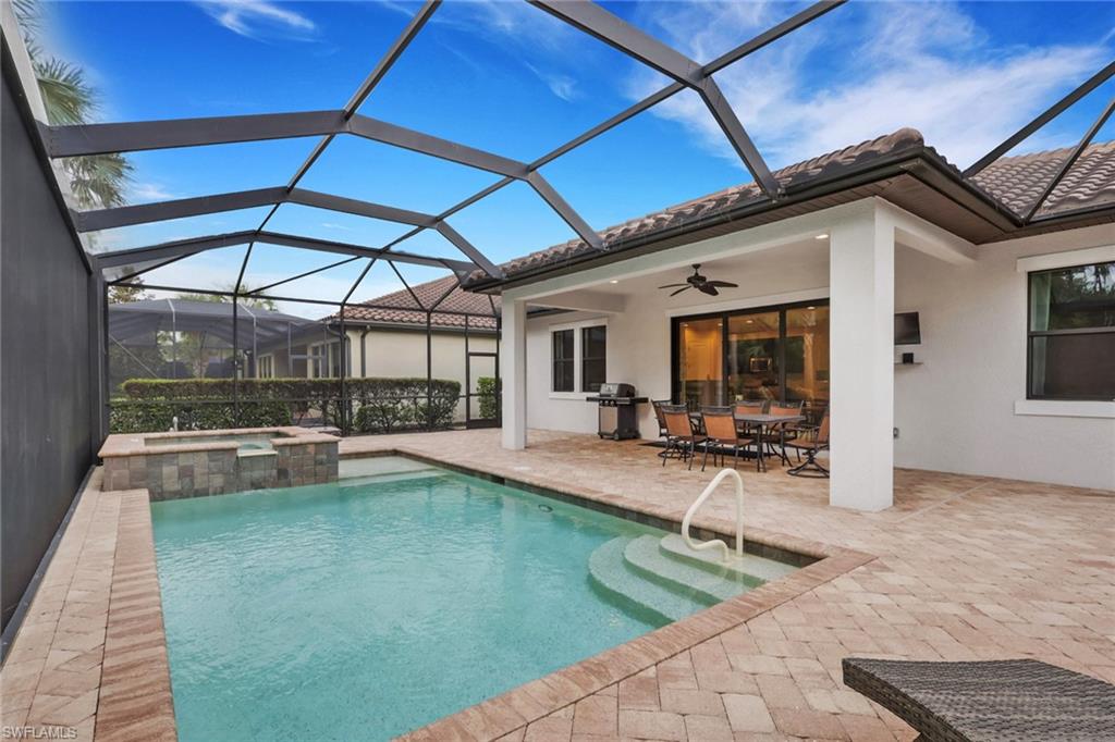 Screened backyard pool beside a covered lanai with outdoor dining furniture.