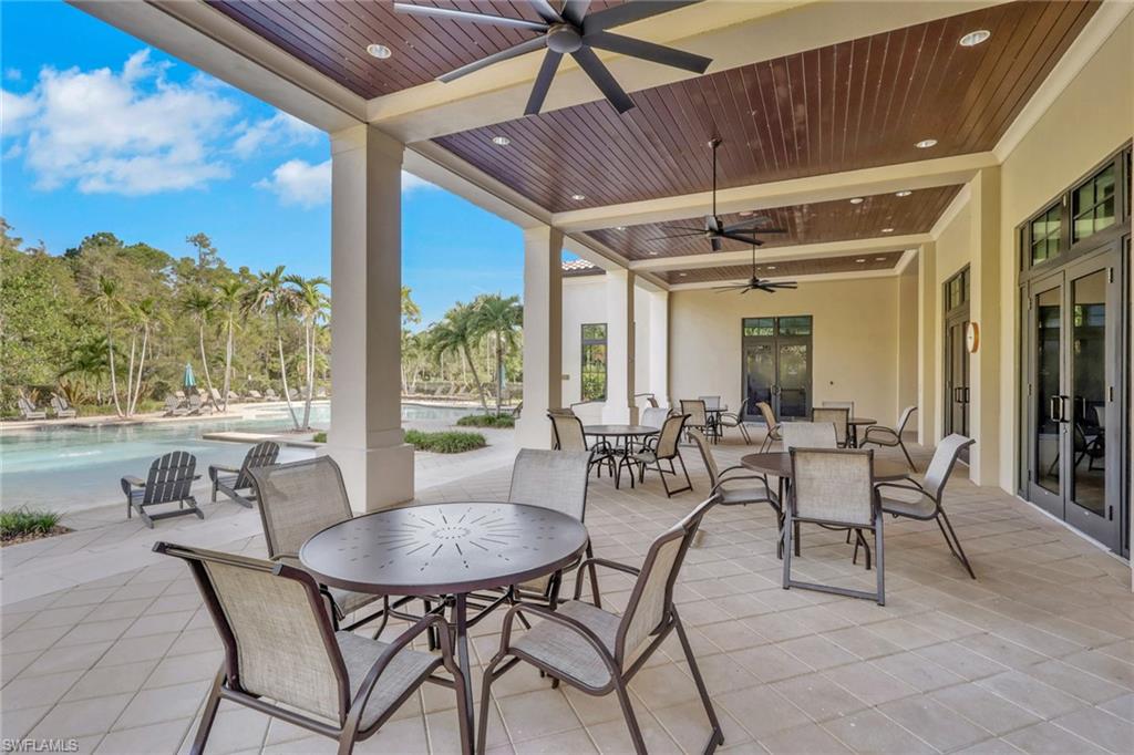 Covered patio with ceiling fans, outdoor dining furniture, and a swimming pool beyond.