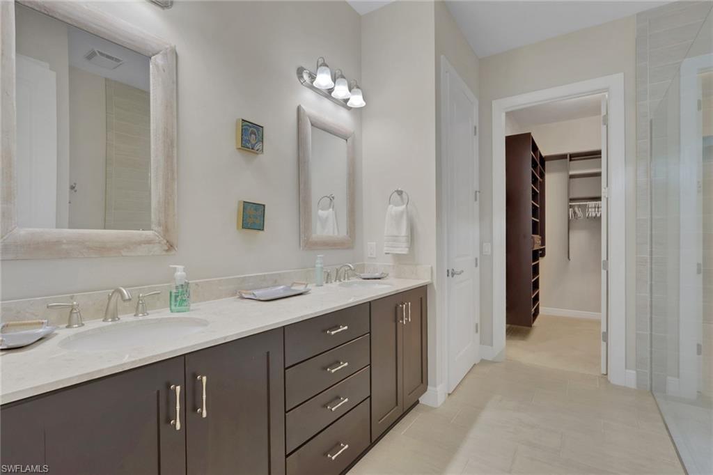 Primary bathroom with a double-sink vanity and an open doorway to a walk-in closet.