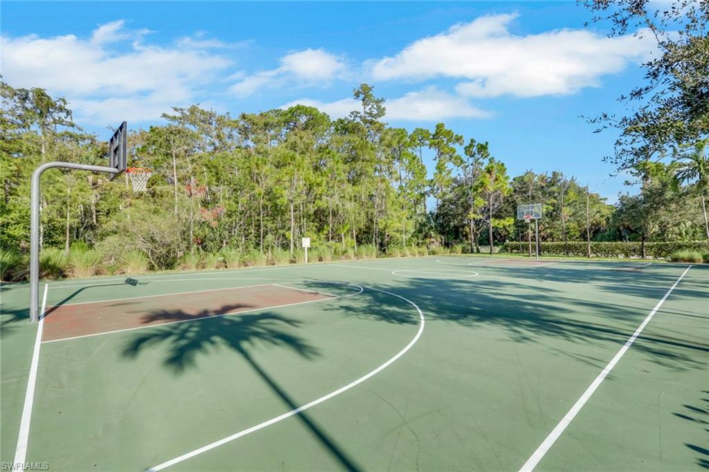 Outdoor basketball court with two hoops, shaded by surrounding trees.